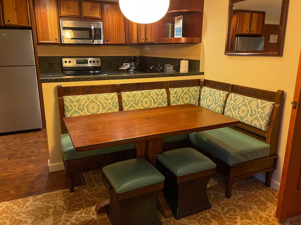 Image of a kitchen table with booth seating and a full kitchen in the background.