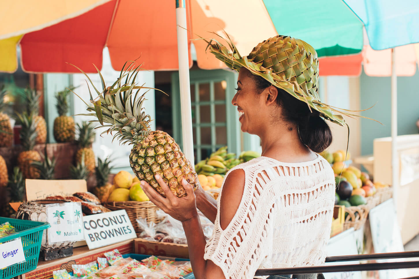 Find out the best farmers markets in Kauai by top Hawaii blog Hawaii Travel with Kids. Image of a woman holding up a pineapple at a Kauai farmers market.