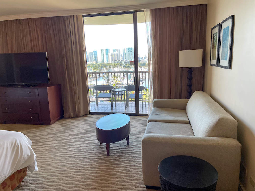 Image of a beige couch, coffee table, and sliding glass door out to the lanai.