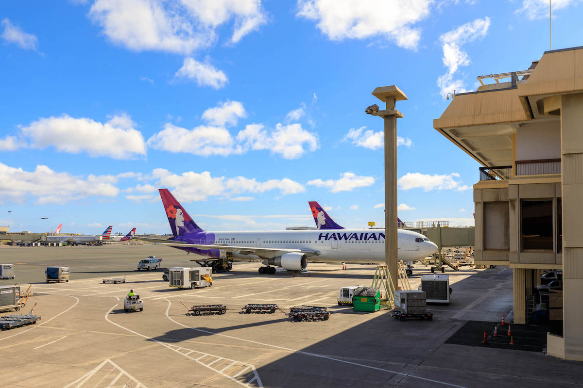 Find out top Honolulu airport tips by top Hawaii blog Hawaii Travel with Kids. Image of a Hawaiian airlines plane at the gate at the Daniel K. Inouye International Airport.