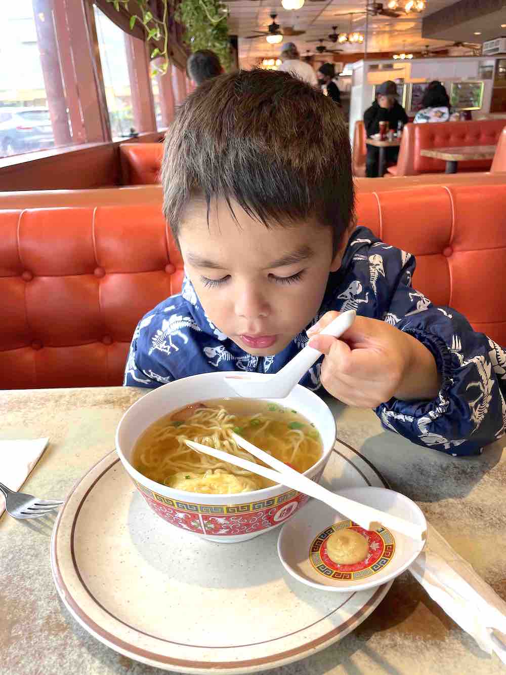 Image of a boy eating soupy noodles at Ken's House of Pancakes