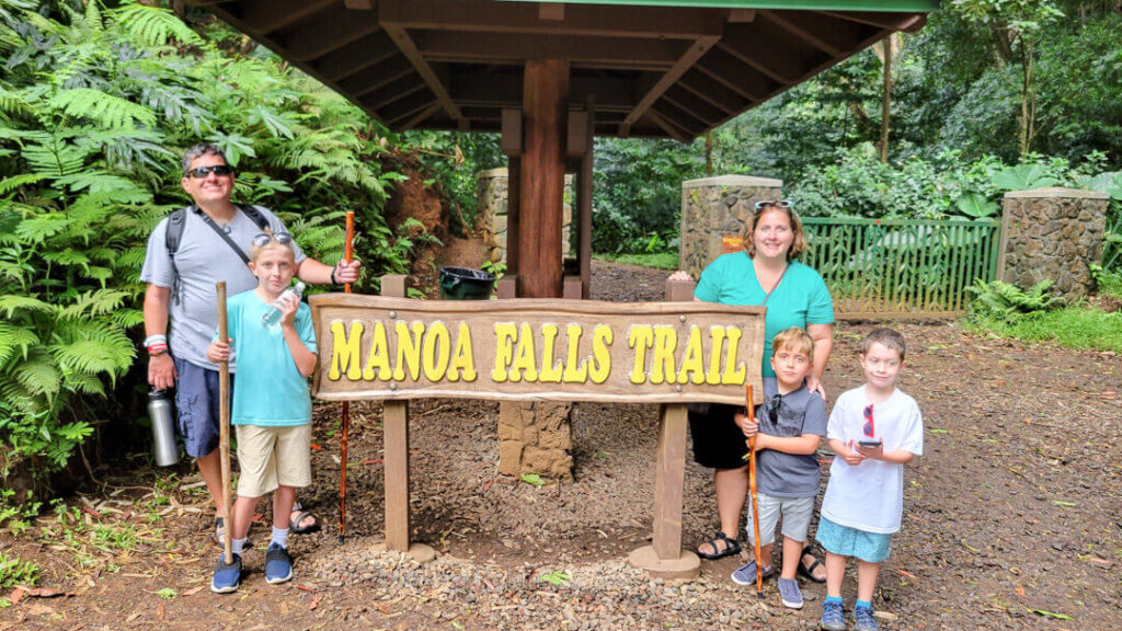 Image of a family of five posing next to the Manoa Falls trail sign on Oahu.