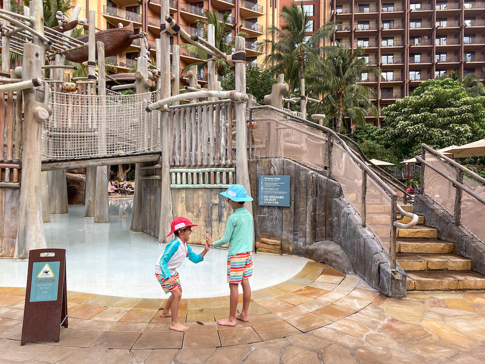 Image of kids high fiving at a water play area at Disney Aulani Resort in Hawaii.