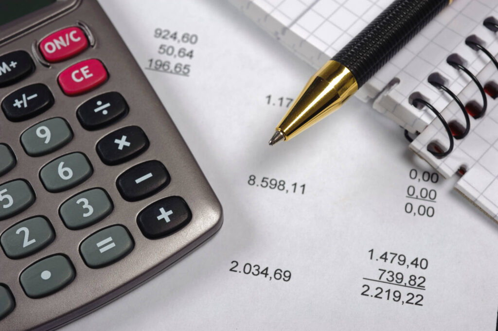 Image of a calculator, pen, and notebook.