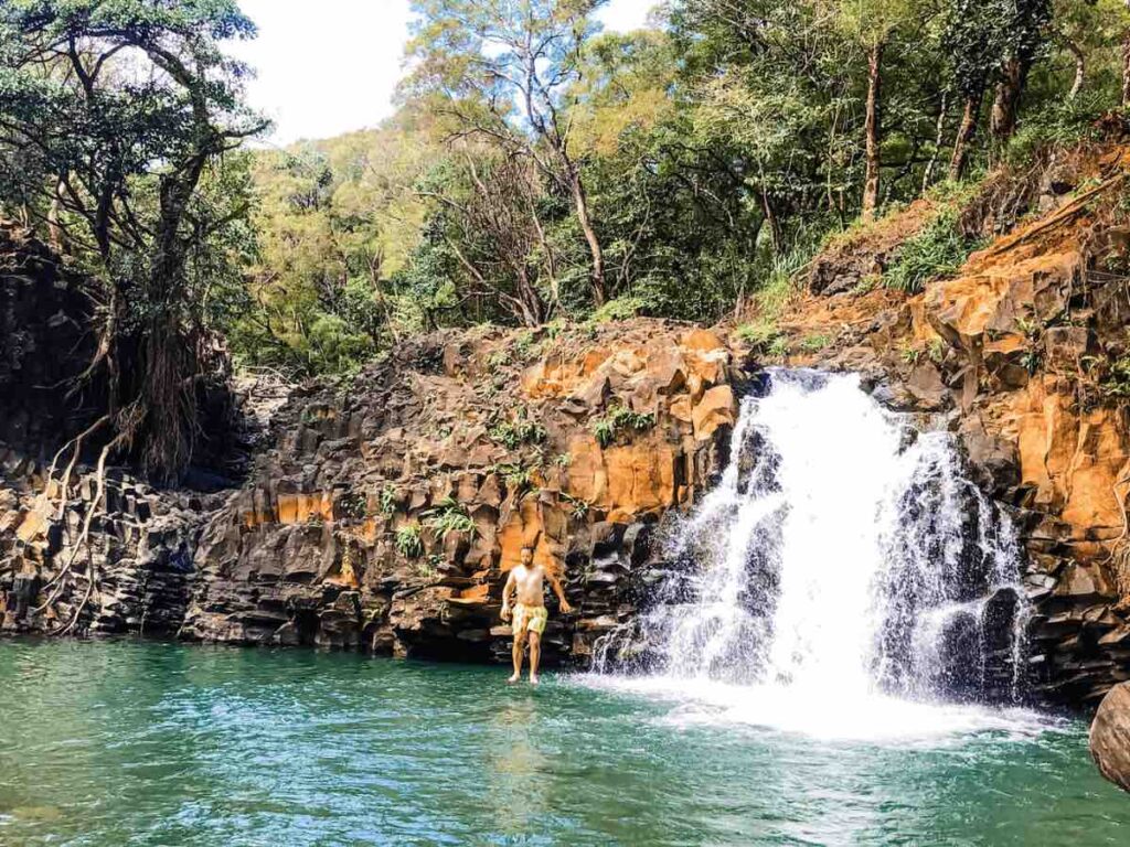 Image of a man jumping into the base of a waterfall on Maui during a Maui waterfall tour.