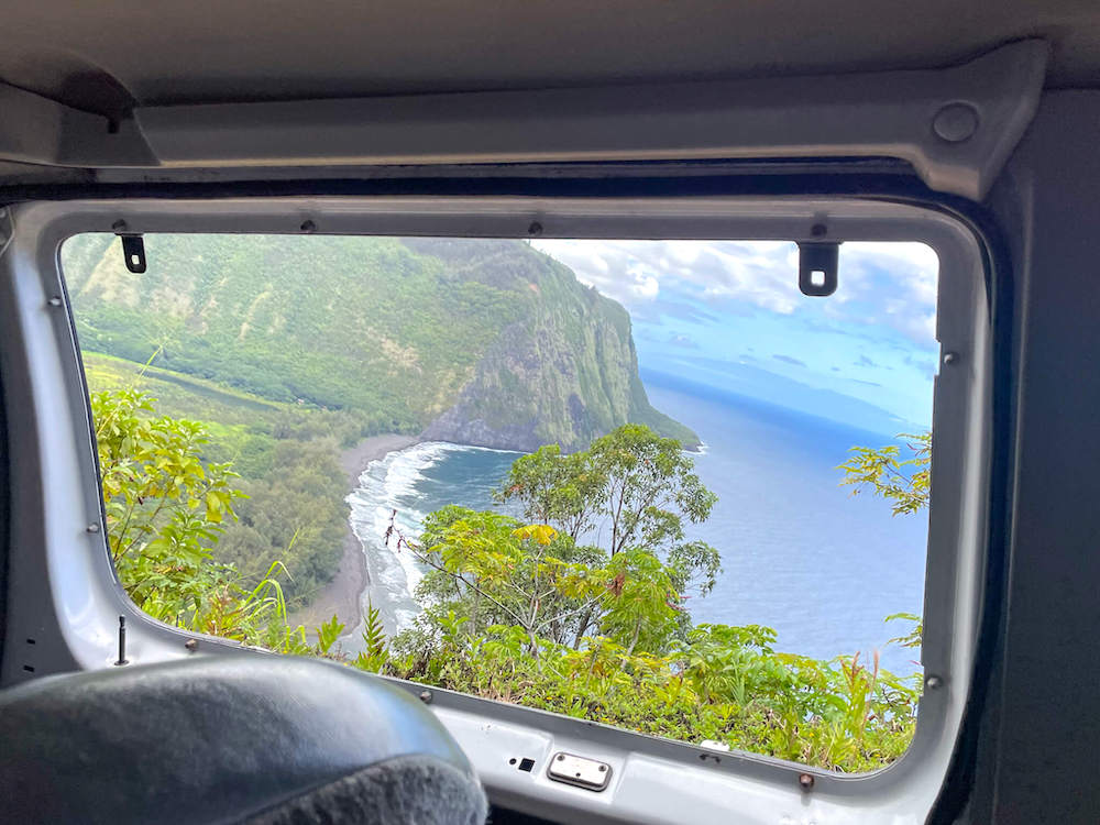 Image of a van window where you can see the Waipio Valley coastline.