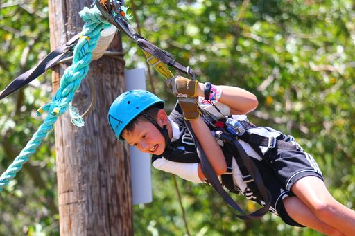 Image of a boy wearing a blue helmet ziplining on Maui with the Camp Maui North Shore zipline tour.