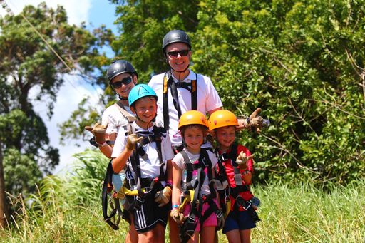 Image of a family wearing ziplining gear as they get ready to go on the Camp Maui North Shore Zipline Tour.