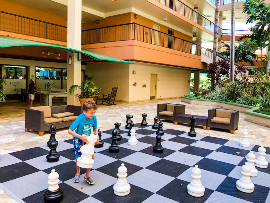 Image of a boy moving a huge chess piece at an outdoor chess board at the Marriott Maui Ocean Club in Hawaii.