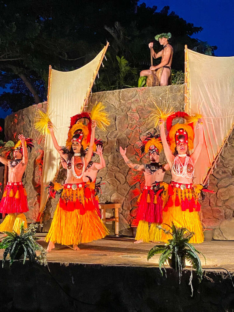 Image of male and female Tahitian dancers in red and yellow costumes at a Wailea luau.