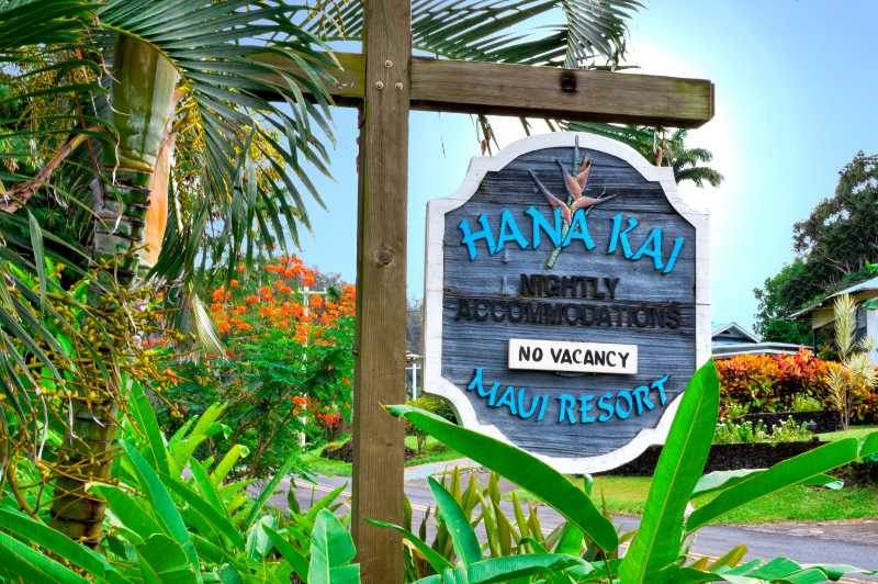 Image of the Hana Kai Maui Resort sign surrounded by tropical plants.