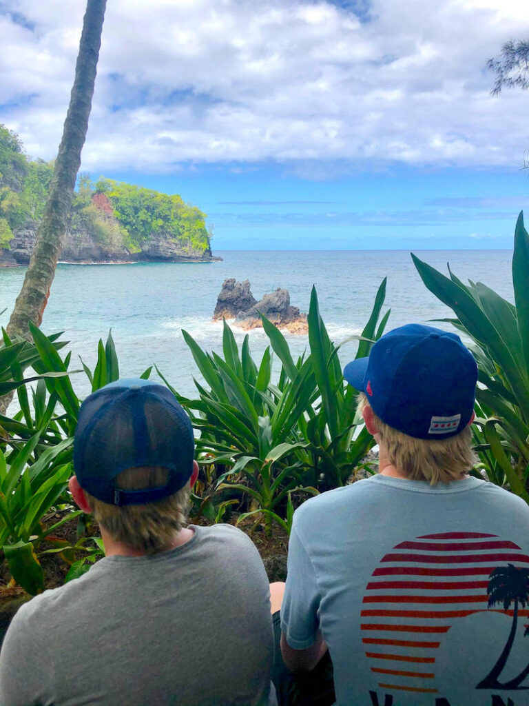 Image of two teens sitting and looking at the ocean from the Hawaii Tropical Bioreserve & Garden in Hilo Hawaii.