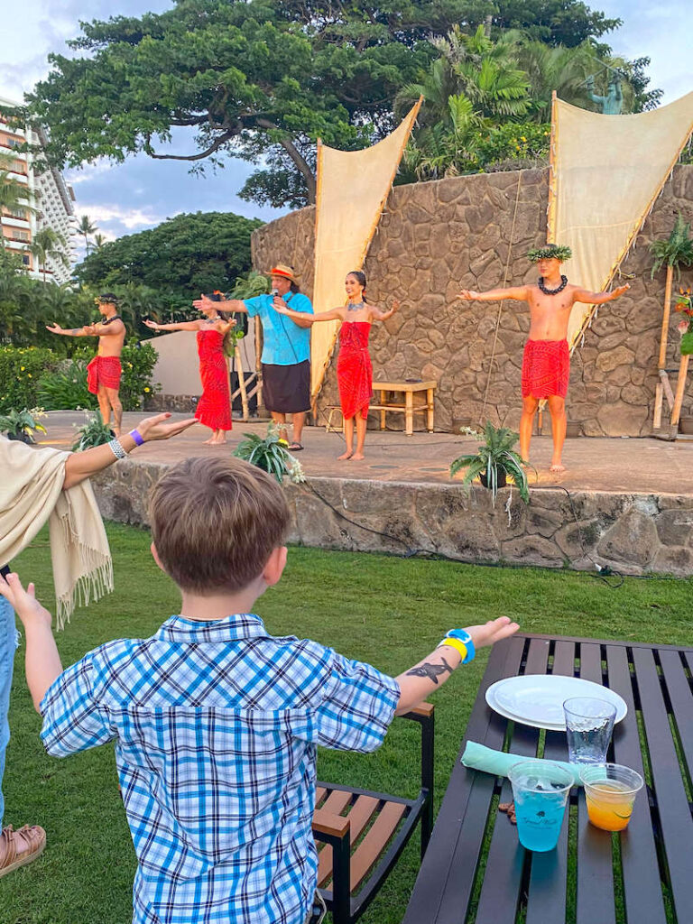 Image of a boy learning how to dance hula at the Grand Wailea Luau on Maui.