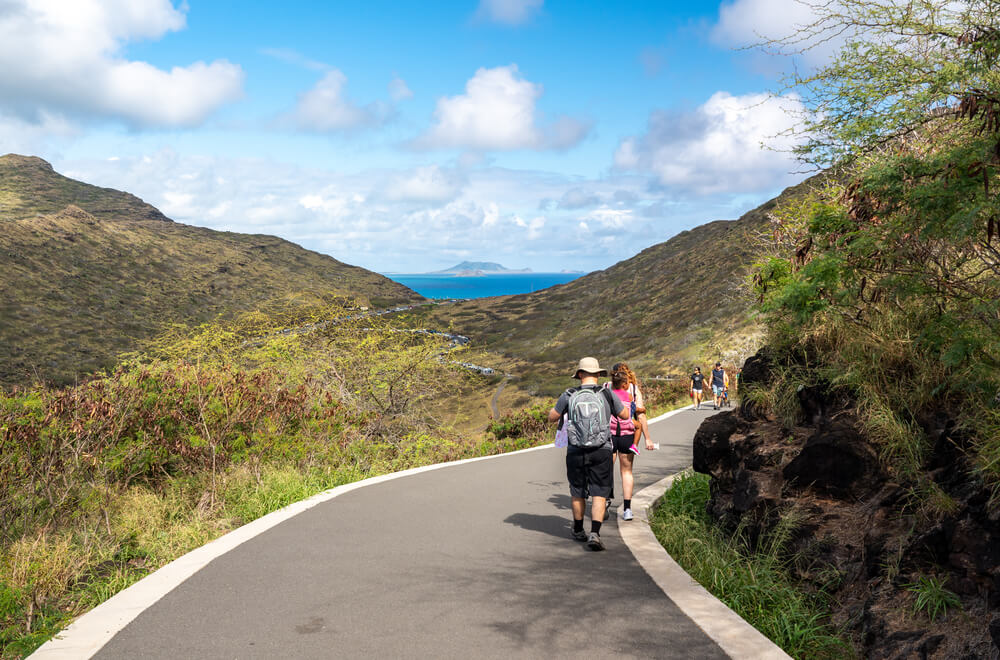 Image of people walking on a paved path to Makapuu Lighthouse in Oahu Hawaii.