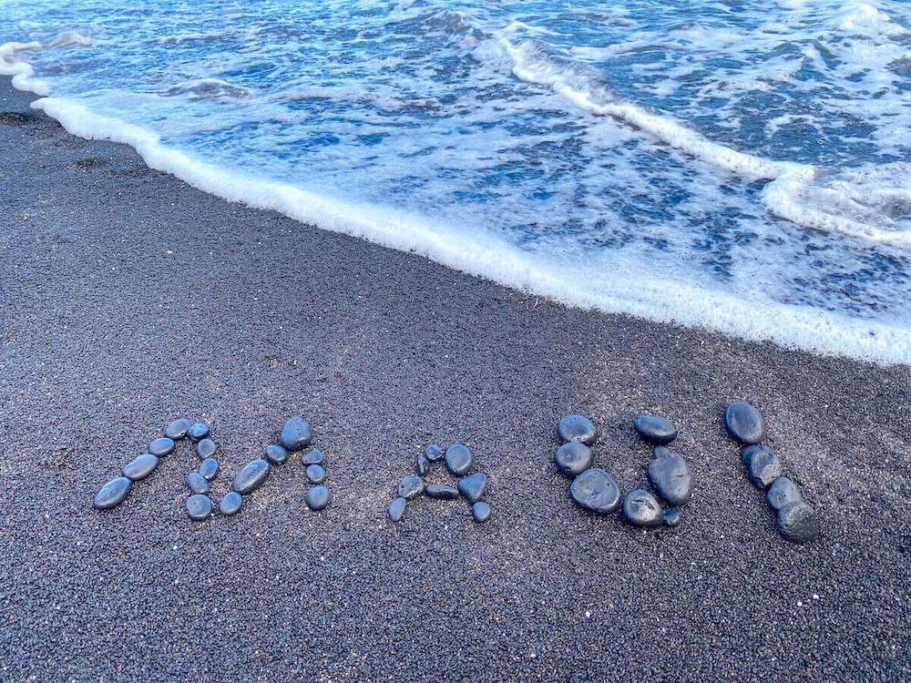 Image of the word Maui spelled out in rocks at the Hana black sand beach.