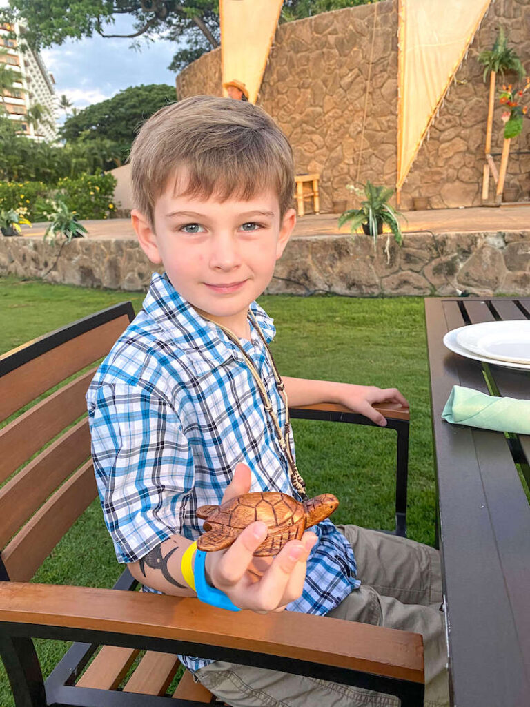 Image of a boy holding a turtle carved out of wood that he bought at the Grand Wailea luau on Maui.