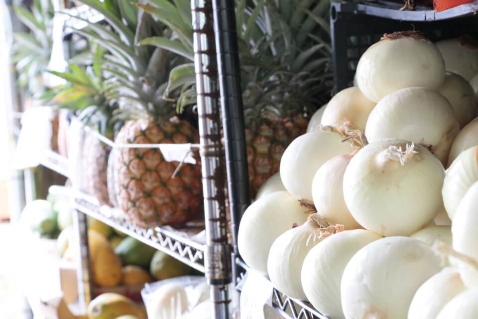 Image of a shelf with white onions and pineapple at the Kona Farmers Market on the Big Island of Hawaii.