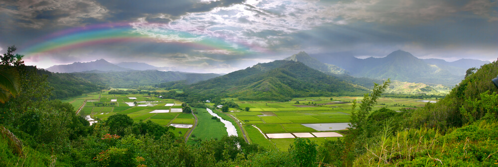 Image of a green valley on Kauai with a rainbow over it