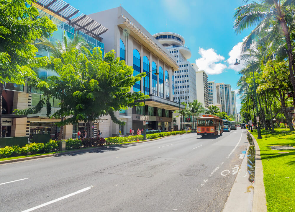 Image of a trolley driving down Kalakaua Avenue in Waikiki on Oahu.