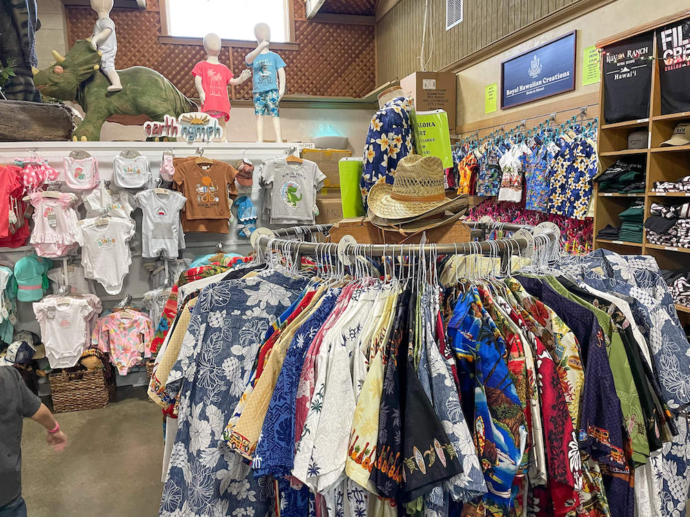 Image of a rack of Aloha shirts with baby clothes in the background.