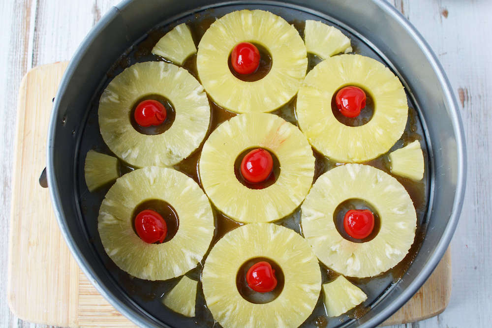 Image of a springform pan with pineapple rings and cherries.