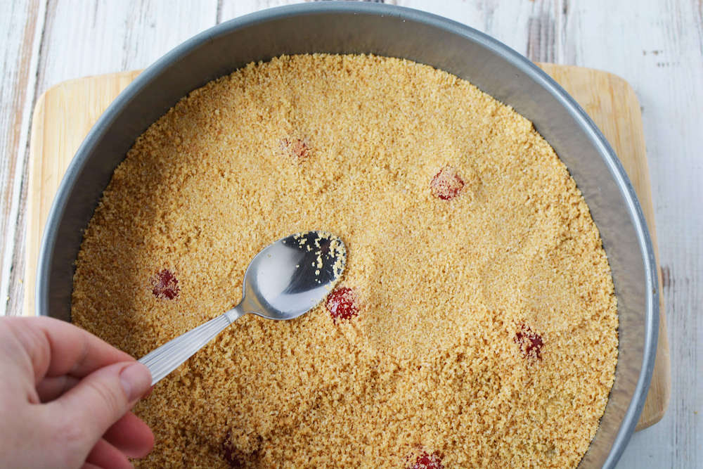 Image of someone pressing graham cracker crust with a spoon