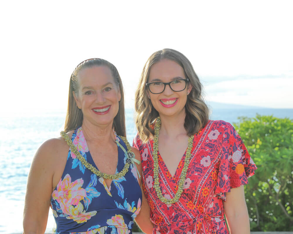 Image of two women wearing dresses and green shell leis at the Feast at Mokapu on Maui.