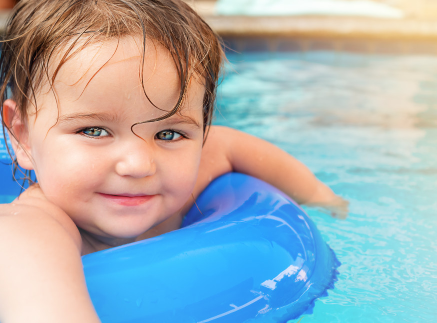 Image of a baby in a pool floatie in a swimming pool