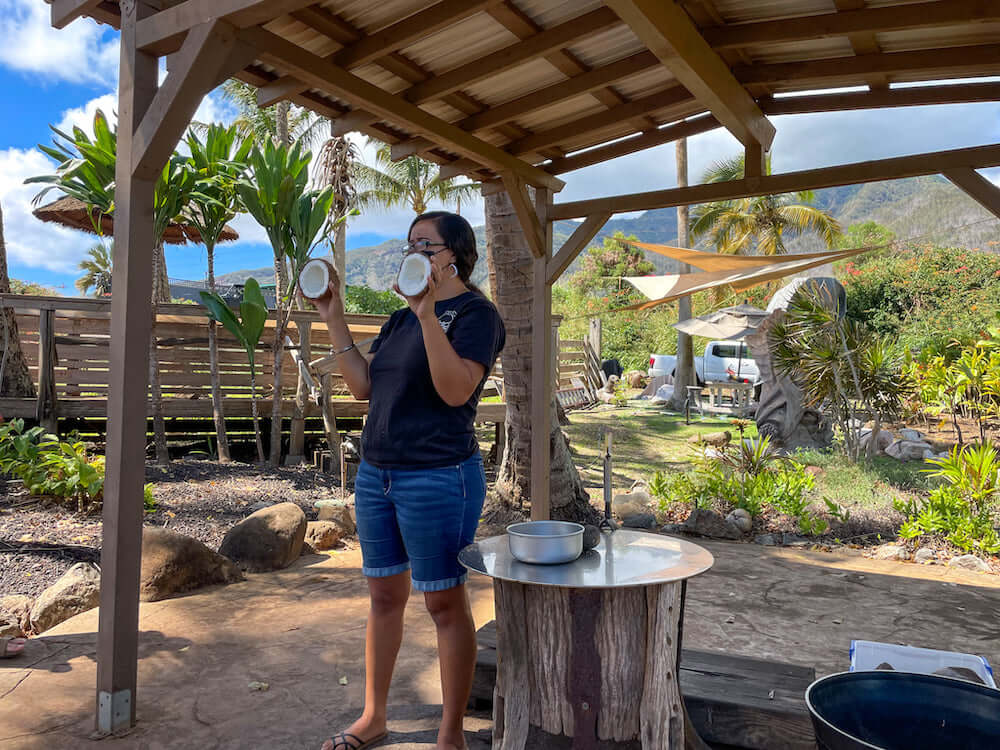 Image of a woman holding up two halves of a fresh coconut at Maui Tropical Plantation in Hawaii.