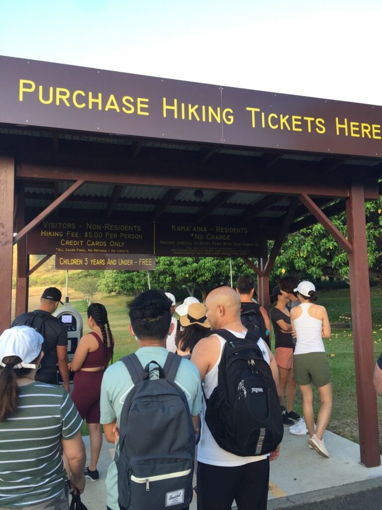 Image of people waiting in line to pay at a ticket machine to climb up Diamond Head hike on Oahu