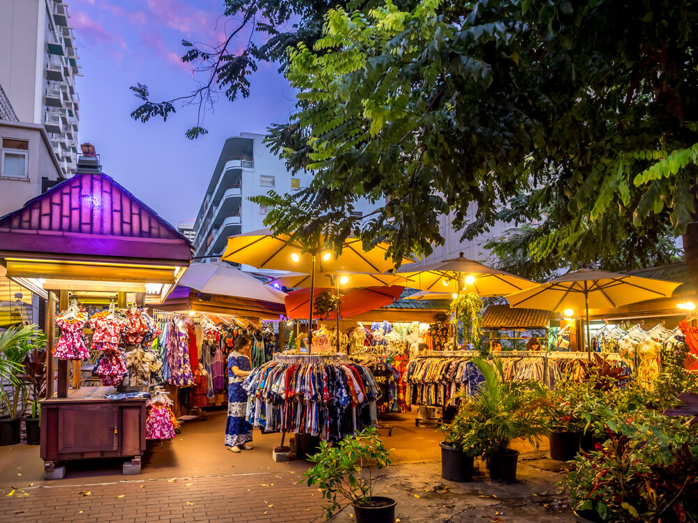 Image of an outdoor shopping area with racks of Aloha shirts at Duke's Marketplace in Waikiki Oahu.