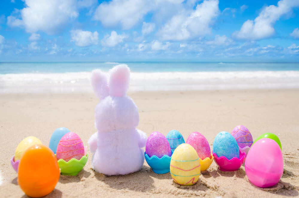 Image of a little Easter bunny and a bunch of plastic eggs on the beach in Hawaii.