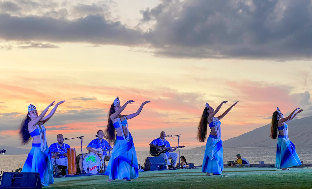 Check out this honest Feast at Mokapu Andaz Maui Luau review by top Hawaii blog Hawaii Travel with Kids. Image of hula dancers and a band performing with the ocean and sunset in the background.