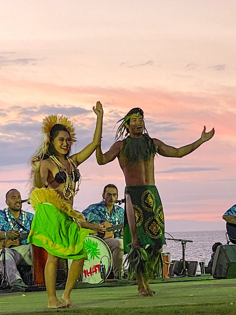 Image of a man and woman Tahitian dancing wearing green outfits.