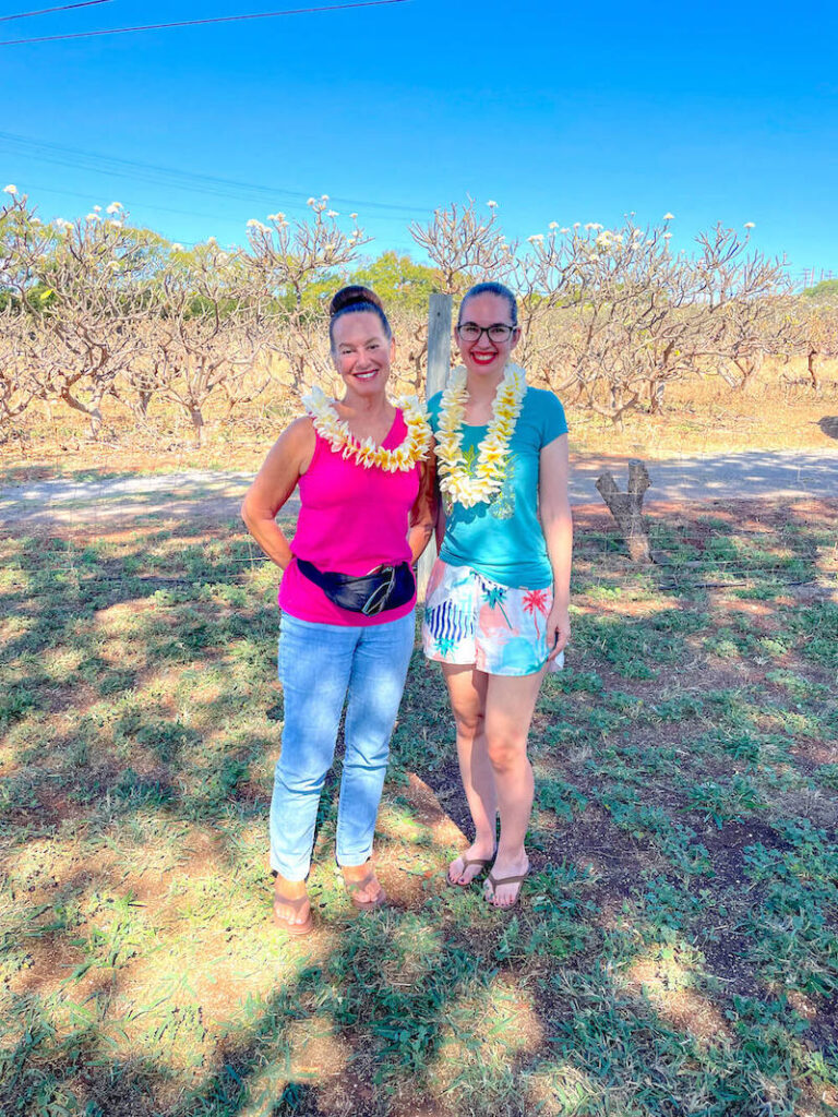 Image of a mom and daughter wearing fresh plumeria leis at a plumeria farm on Molokai.