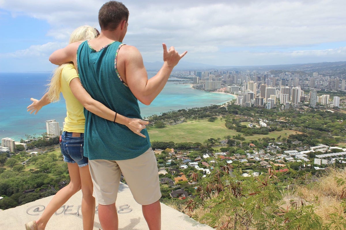 Find out whether it's worth hiking Diamond Head with kids by top Hawaii blog Hawaii Travel with Kids. Image of a couple posing on top of Diamond Head Crater