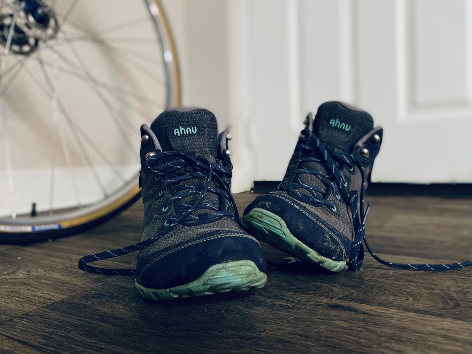 Image of dark hiking boots with a bicycle in the background.
