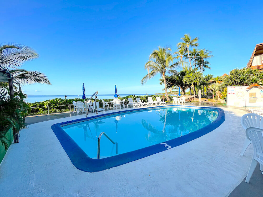 Image of a swimming pool with white chairs grouped around it.