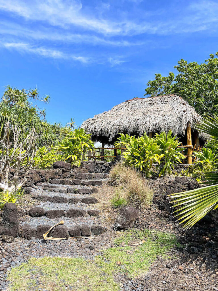Image of stone steps leading to a grass shack at the Kahanu Gardens in Hana Maui