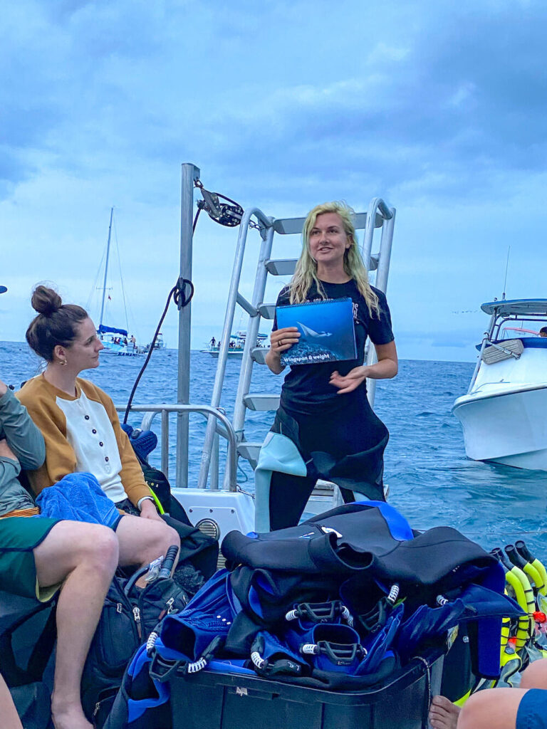 Image of a woman wearing a wetsuit on a boat with people in regular clothing.