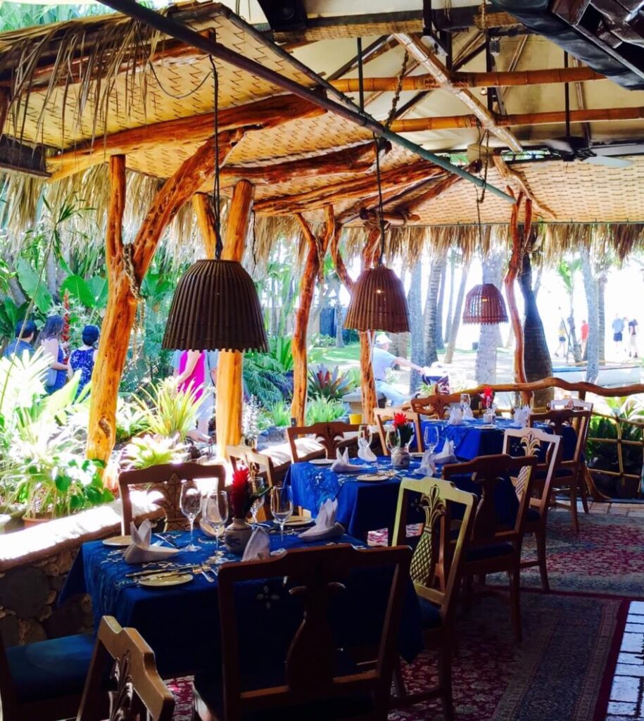 Image of the inside of Mama's Fish House, with blue tablecloths and brown hanging lights.