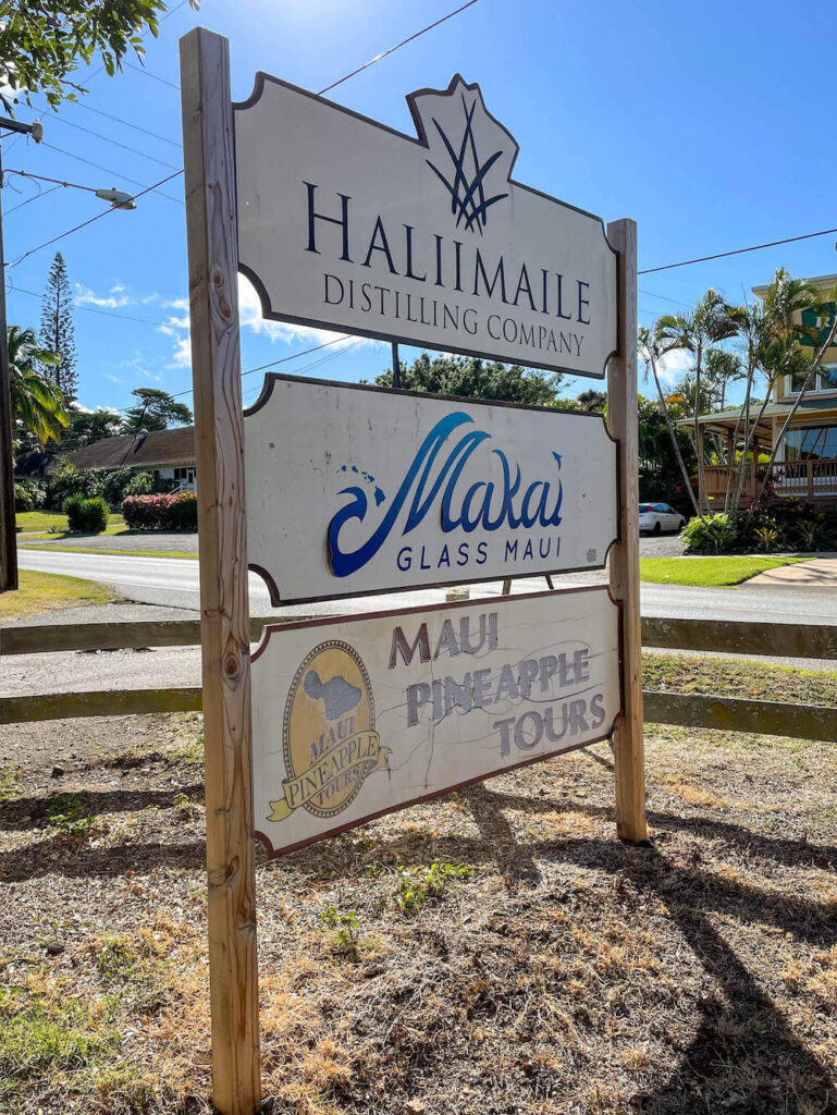 Image of a roadside sign promoting the Haliimaile Distilling Company, Makai Glass Maui, and Maui Pineapple Tours.