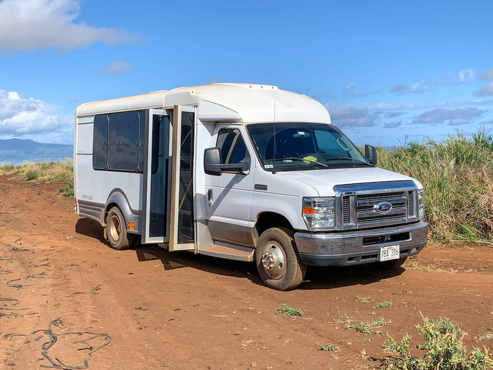 Image of a small luxury van in the middle of a Maui pineapple farm