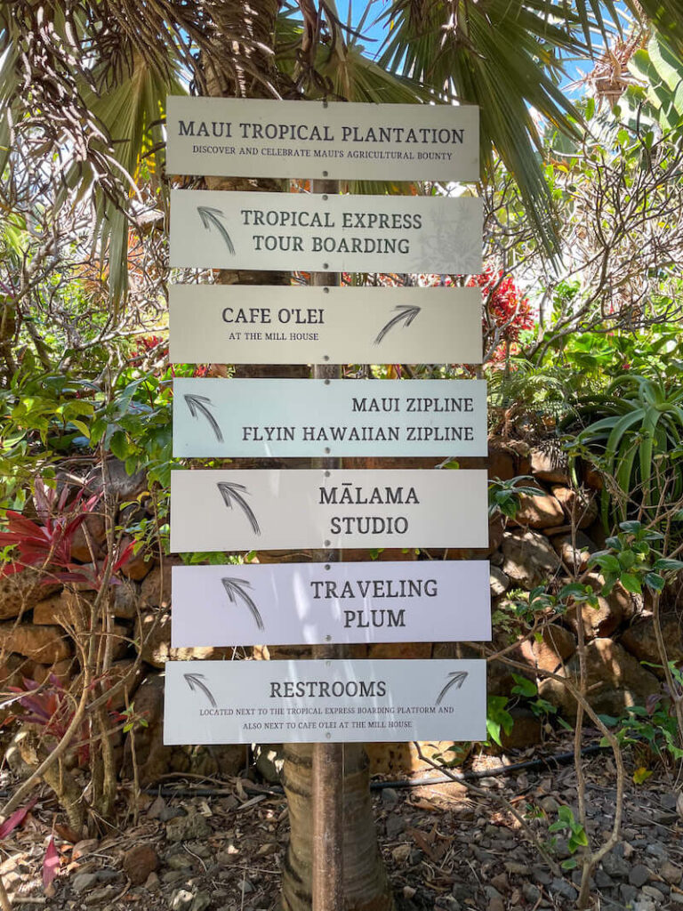 Image of a post with a bunch of small signs attached with directions to things to do at Maui Tropical Plantation.