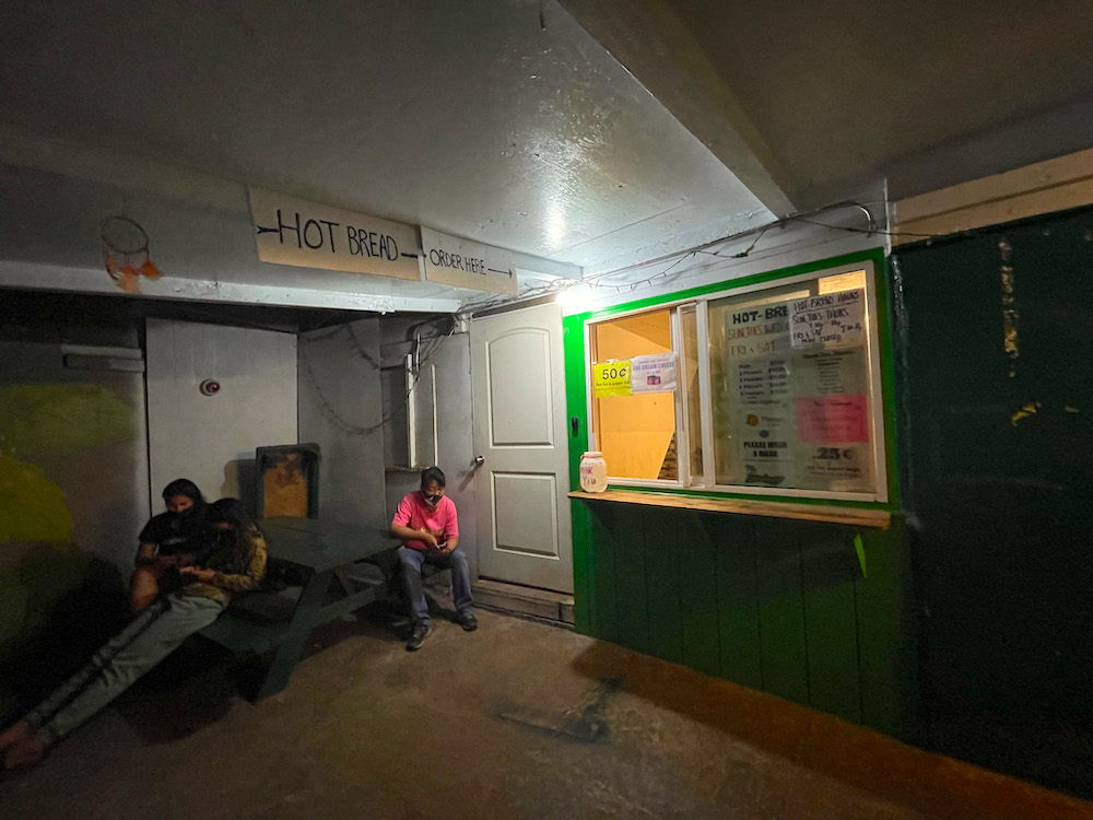 Image of an alley way with a window where you order hot bread on Molokai.