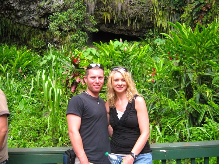 Image of a man and woman posing for a photo in front of Fern Grotto on Kauai.