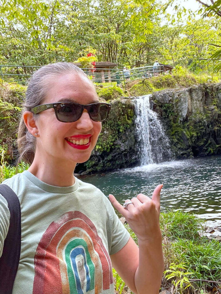 Image of a woman taking a selfie with a waterfall along the Road to Hana on Maui