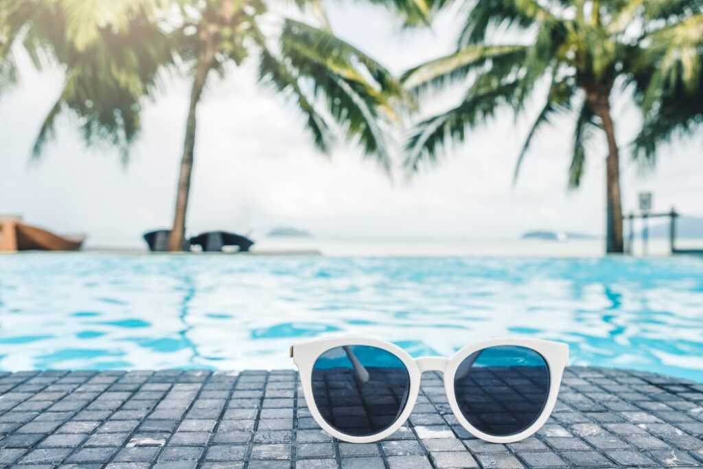 Image of white sunglasses by a tropical pool