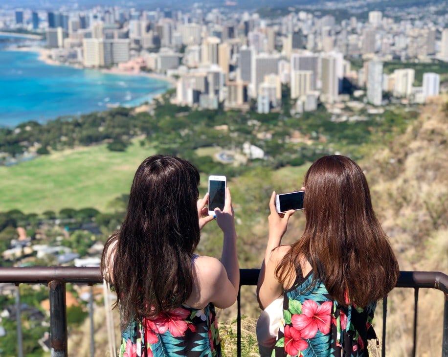 Image of two women taking cellphone photos from Diamond Head