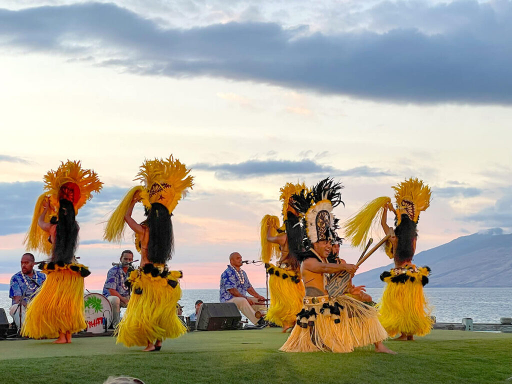 Image of some Tahitian dancers wearing yellow costumes dancing on a grassy stage in Maui.
